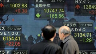 Men look at an electric quotation board flashing some key stock market indexes from around the world in front of a securities company in Tokyo on January 21, 2013.