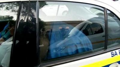 Oscar Pistorius hiding under a blanket in a police car