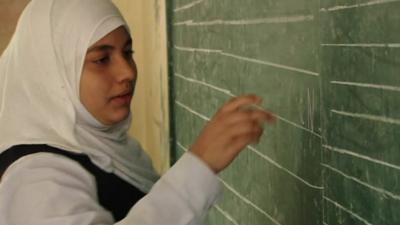 A school girl writes in Hebrew on a blackboard