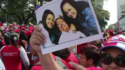 A supporter holds up a picture of Hugo Chavez and his daughters