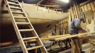 Jonah Eaton works on his wooden yacht