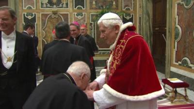 A cardinal kisses Pope Benedict's hands