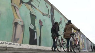 Women on bicycles walking past Wall mural