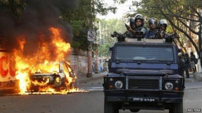 A police van passes a burnt vehicle after activists of Bangladesh Nationalist Party (BNP) set fire to it during a clash in Dhaka March 2, 2013