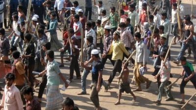Jamaat-e-Islami activists march with sticks and set fires in the street during a clash with police in Chittagong
