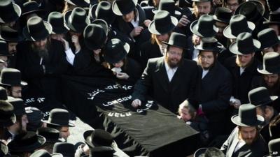 Mourners surround a casket at the Glauber funeral