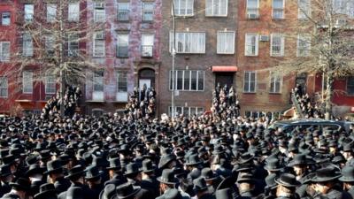 Orthodox Jewish mourners gather outside a synagogue in Brooklyn