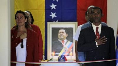 People mourn beside a portrait of the late President Hugo Chavez during a vigil in Venezuela's embassy in Havana