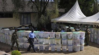 Armed security officers guard ballot boxes that have yet to be tallied