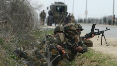 Indian soldiers take positions outside a school after an attack against Indian paramilitary personnel in Srinagar .