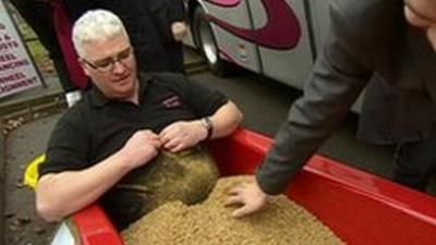 Coach driver Paul Johnston sitting in a bath of maggots