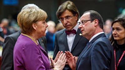 German Chancellor Angela Merkel, peaks with French President Francois Hollande, during a round table meeting at an EU summit in Brussels