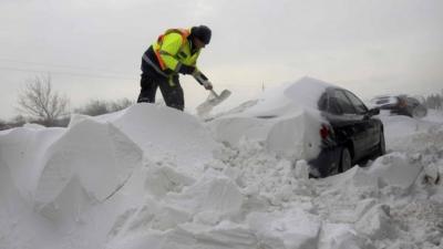 A member of the Hungarian rescue team removes snow from a car at the M1 highway