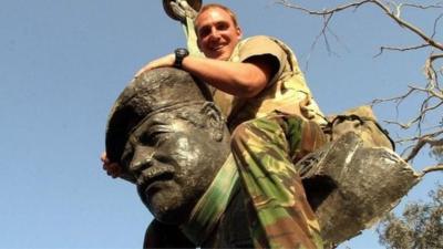 Member of armed forces on toppled Saddam Hussein statue