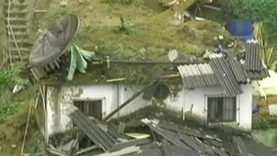 House missing its roof, covered in mud and debris from landslide