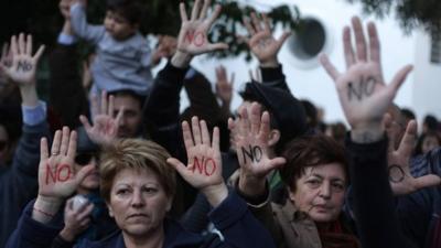 Cypriots show their palms reading "No" during a protest against an EU bailout deal outside the parliament in Nicosia on Monday