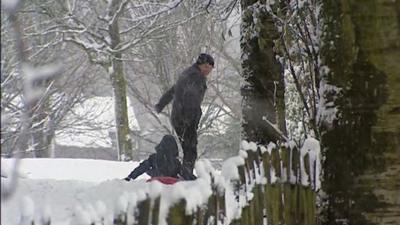 Man pulling a child along on a sledge