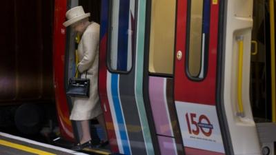 Queen Elizabeth II steps off a parked train she was shown around at Baker Street underground station