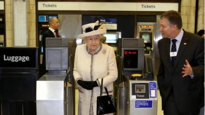 The Queen walks through a ticket barrier