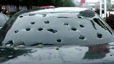 A car windshield punctured with hailstones