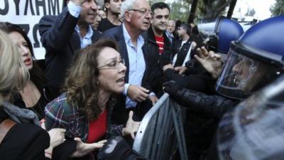 A woman shouts at policemen during a protest outside the parliament in Nicosia