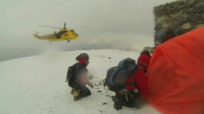 Mountain rescue helicopter landing near climbers in Snowdonia