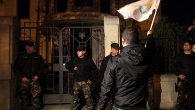 A Cypriot waves the national flag during a protest outside EU House in Nicosia