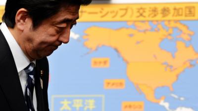 Japanese Prime Minister Shinzo Abe walks before the map of the Trans-Pacific Partnership participating countries