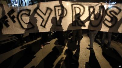 Protesters hold a banner that reads 'Hands off Cyprus' during an anti-bailout rally