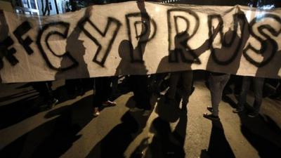 Protesters hold a banner that reads 'Hands off Cyprus' during an anti-bailout rally