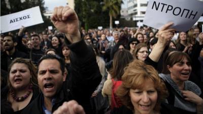 Employees of the Bank of Cyprus shout slogans as they holds banners reading in Greek "shame" during a protest at Cyprus central bank in Nicosia