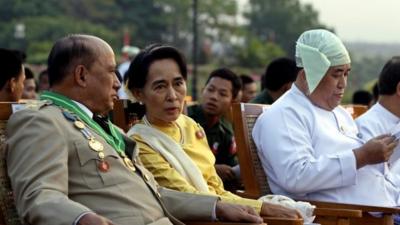 Opposition leader Aung San Suu Kyi, in yellow, talks with Deputy Border Affairs Minister Maj. Gen. Zaw Win, left, during Myanmar's 68th anniversary celebrations of Armed Forces Day, in Naypyidaw, Myanmar, Wednesday, March 27, 2013.