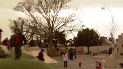 An aeroplane flies over a school in west London