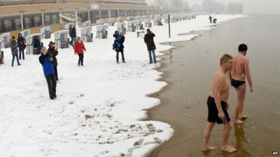 First swimmers of the season walk into the water at the snowy beach of Strandbad Wannsee in Berlin