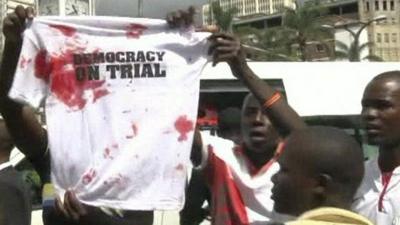 Supporters of Raila Odinga holding up T-shirt saying "democracy on trial"