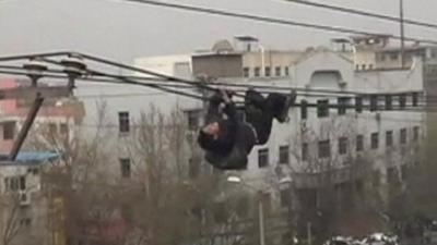 A drunken man climbing a utility pole and crawled along electricity cables in China