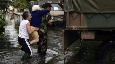 A soldier evacuates an elderly woman in a flooded street in La Plata