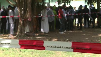 Crowds gather near a mass grave due to be exhumed