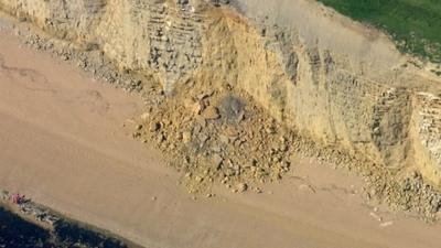 A pile of rock at the foot of a cliff