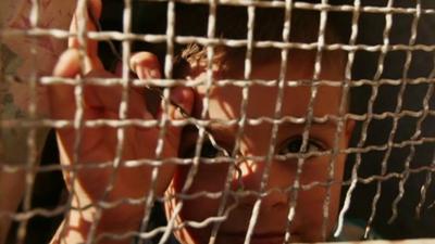 Child looks through metal grill