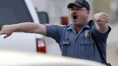 A police officer clears a path for an ambulance after an explosion and gunshots in Georgia