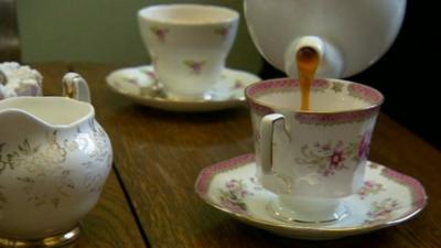 Tea being poured into china cup