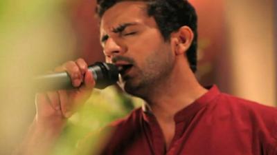 A young Pakistani man sings into a microphone