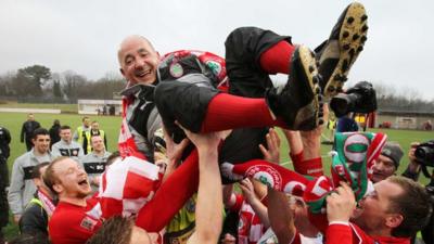 Manager Tommy Breslin is lifted by the players after Cliftonville won the Irish Premiership