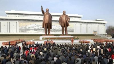 North Korean soldiers, workers and students place flowers before the statues of North Korean founder Kim Il-sung (left) and his son, late leader Kim Jong-il