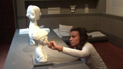 A woman touching a copy of a sculpture