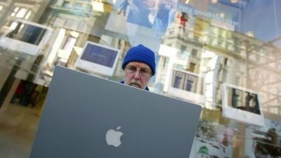 Customer logs onto a laptop whilst waiting for new Apple store in London to open