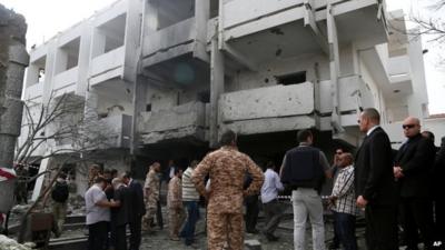 Security officers and officials inspect the site of a car bomb outside the French embassy