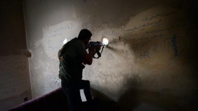 A Syrian rebel observes the movement of regime forces