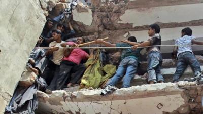 Bangladeshi rescuers squeeze through a gap to help pull out survivors spotted in the debris of a building that collapsed in Savar, near Dhaka